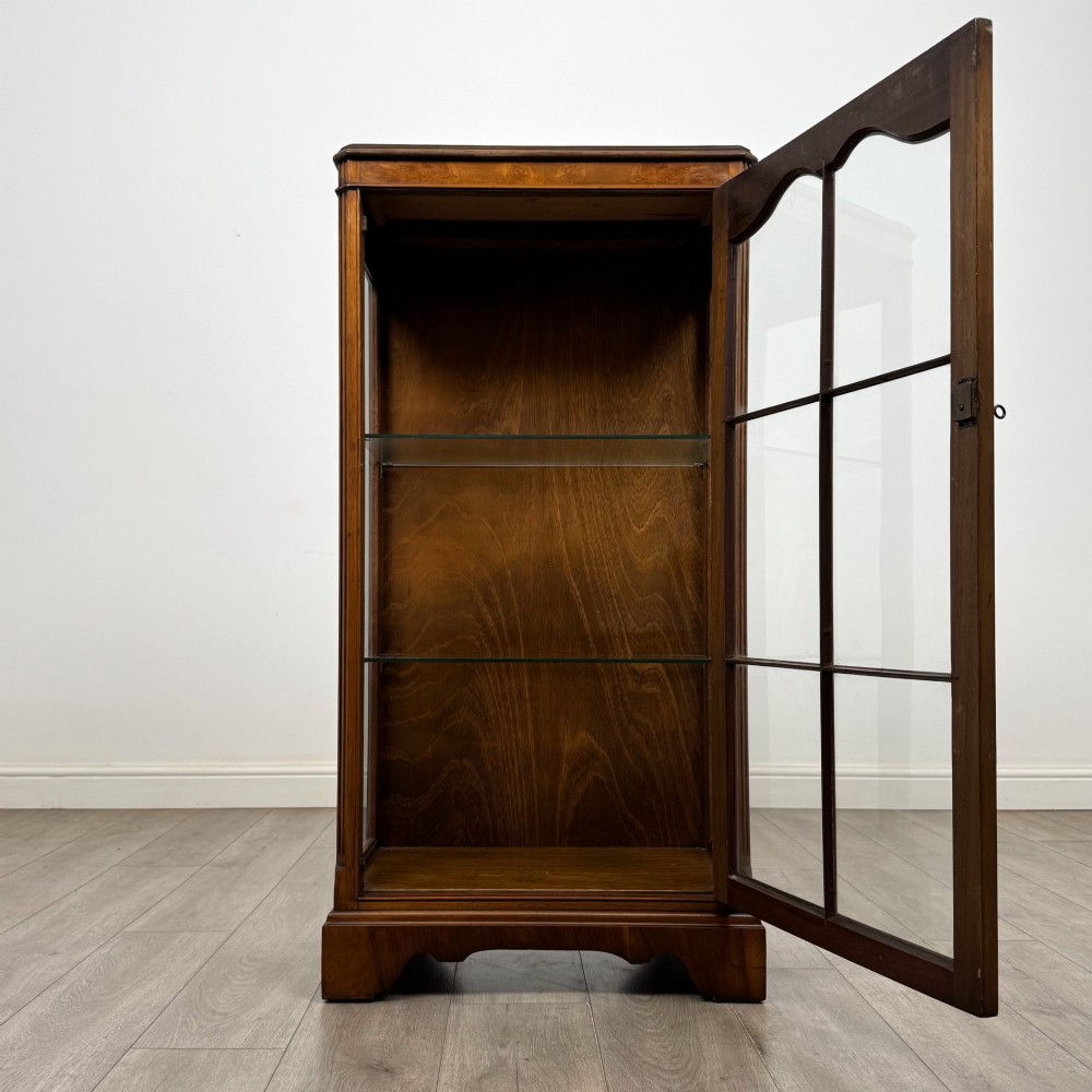A freestanding burr walnut display cabinet featuring a single glazed door with six glass panes, curved upper frame moulding, and a bracket base. View II