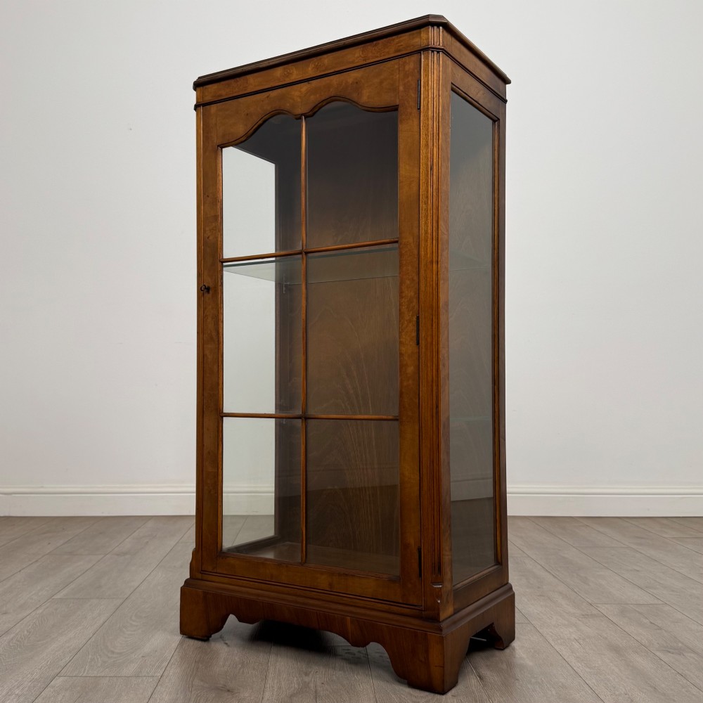A freestanding burr walnut display cabinet featuring a single glazed door with six glass panes, curved upper frame moulding, and a bracket base. View III