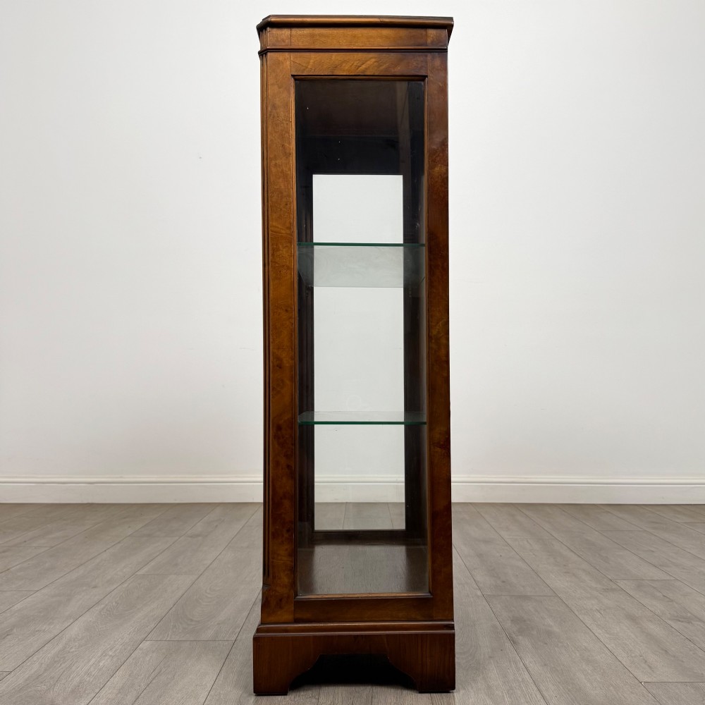 A freestanding burr walnut display cabinet featuring a single glazed door with six glass panes, curved upper frame moulding, and a bracket base. View IV