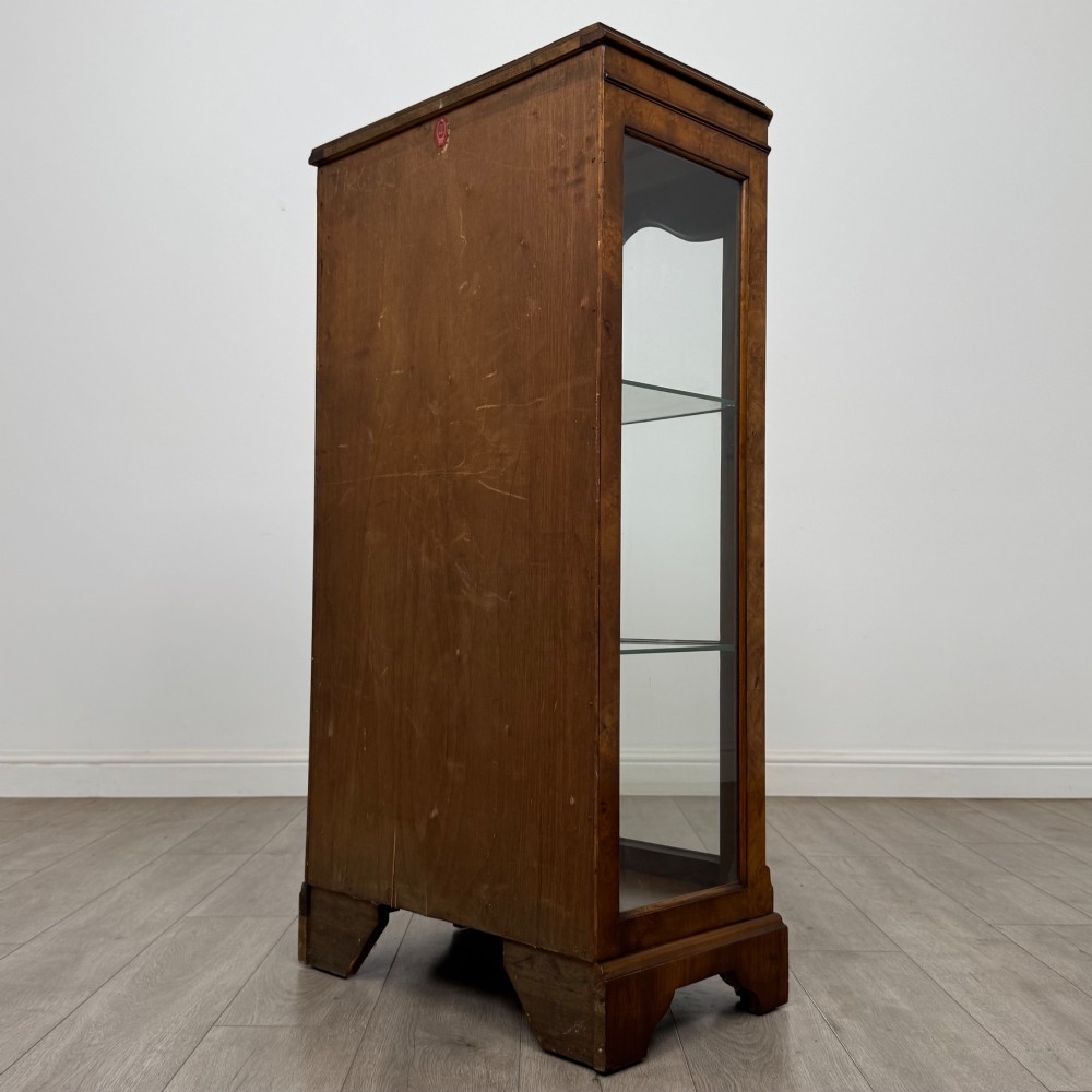A freestanding burr walnut display cabinet featuring a single glazed door with six glass panes, curved upper frame moulding, and a bracket base. View VII