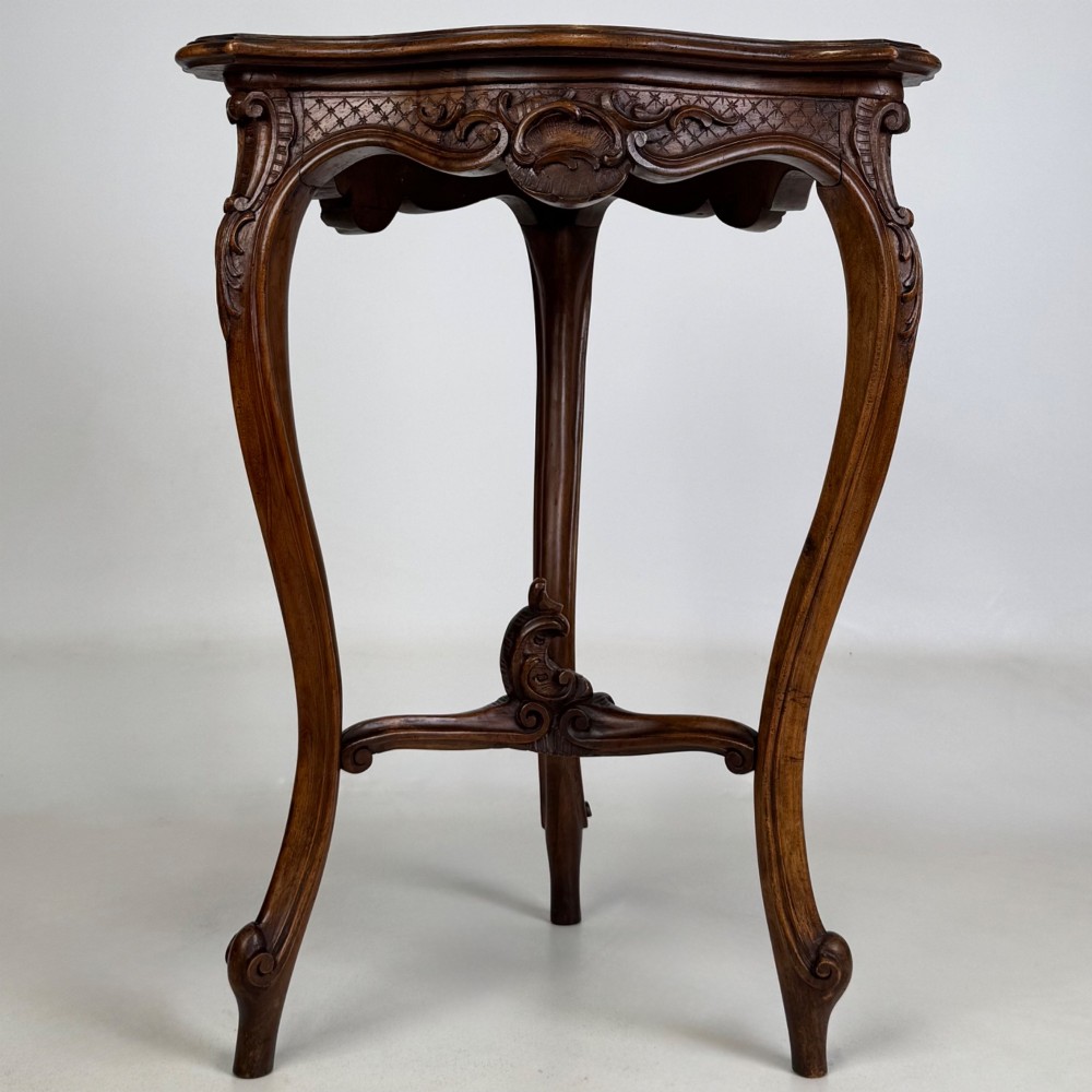 A dark mahogany side table featuring carved cabriole legs, a decorative carved apron with a shell motif, and a sculpted lower cross stretcher. View III