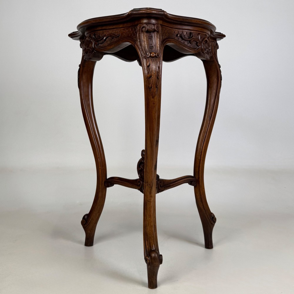 A dark mahogany side table featuring carved cabriole legs, a decorative carved apron with a shell motif, and a sculpted lower cross stretcher. View IV