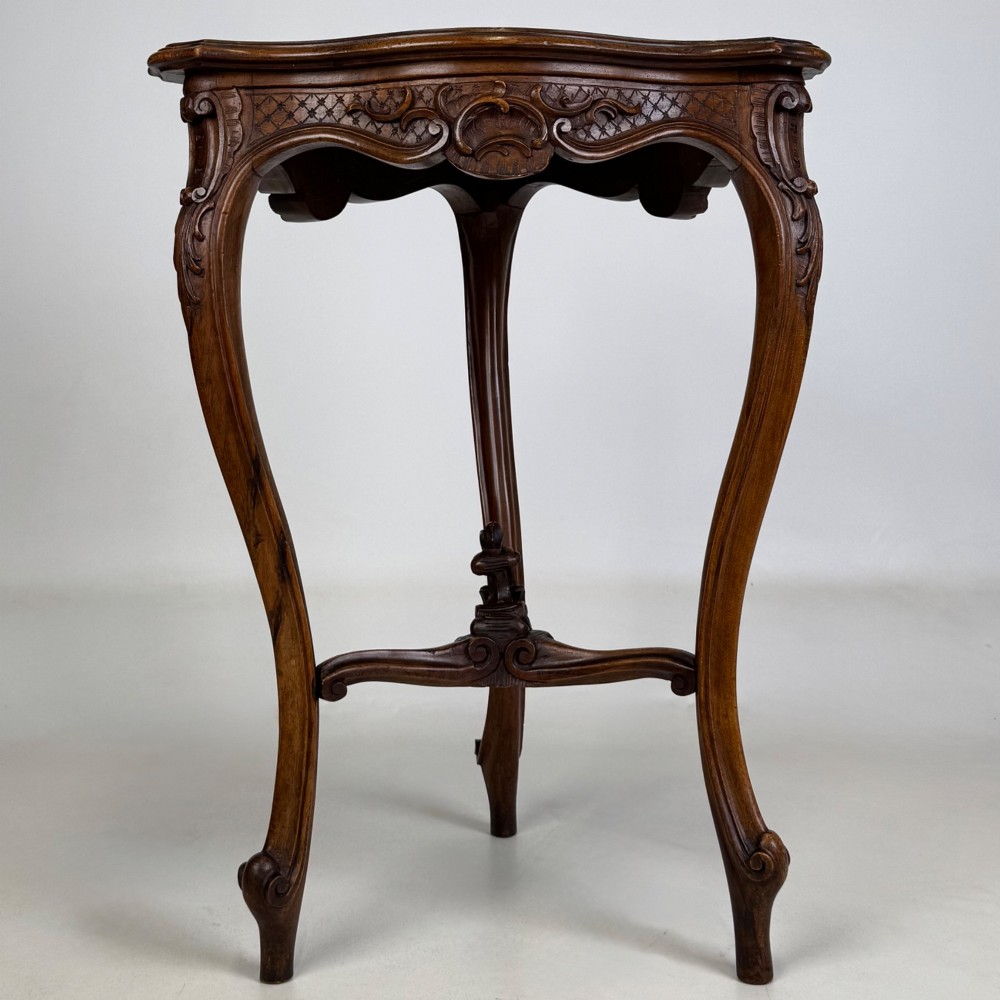A dark mahogany side table featuring carved cabriole legs, a decorative carved apron with a shell motif, and a sculpted lower cross stretcher. View V