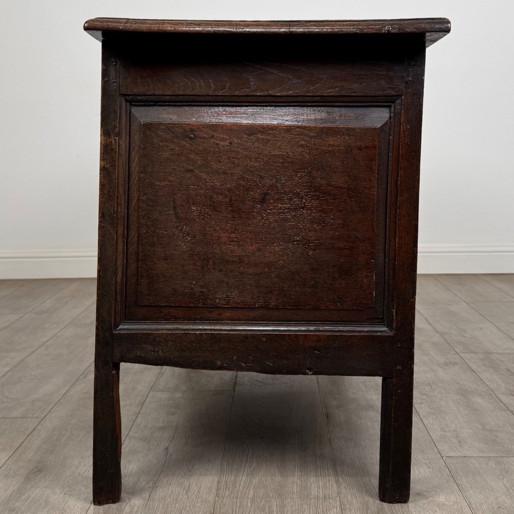 An 18th-century Georgian golden oak coffer featuring three raised panel front section and a carved top rail dated 1723 with initials D H. View III