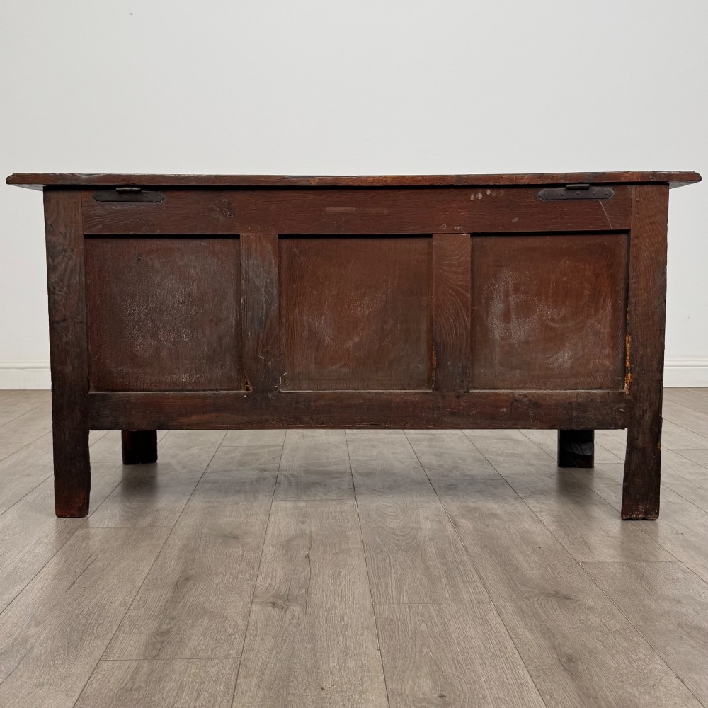 An 18th-century Georgian golden oak coffer featuring three raised panel front section and a carved top rail dated 1723 with initials D H. View V
