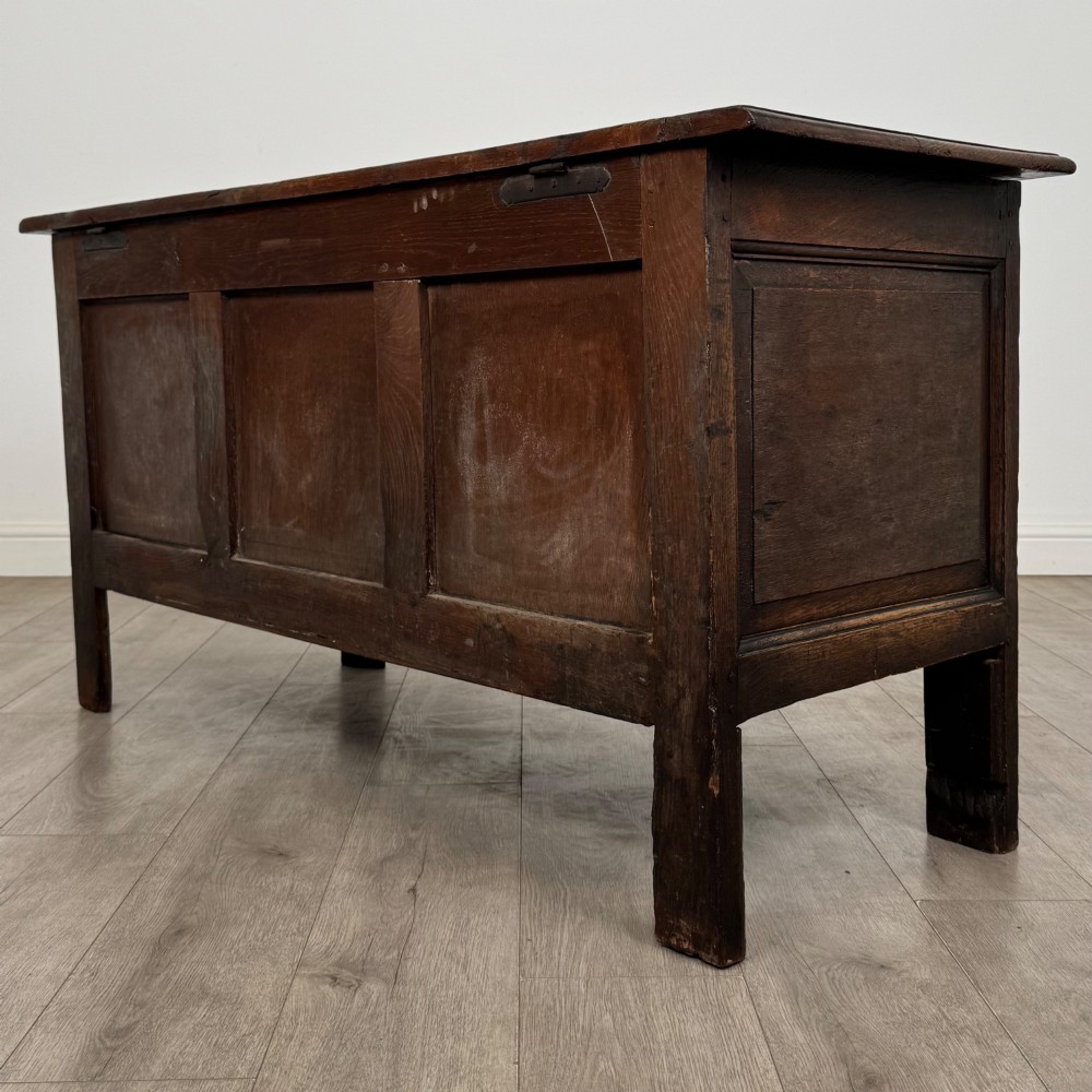 An 18th-century Georgian golden oak coffer featuring three raised panel front section and a carved top rail dated 1723 with initials D H. View VI
