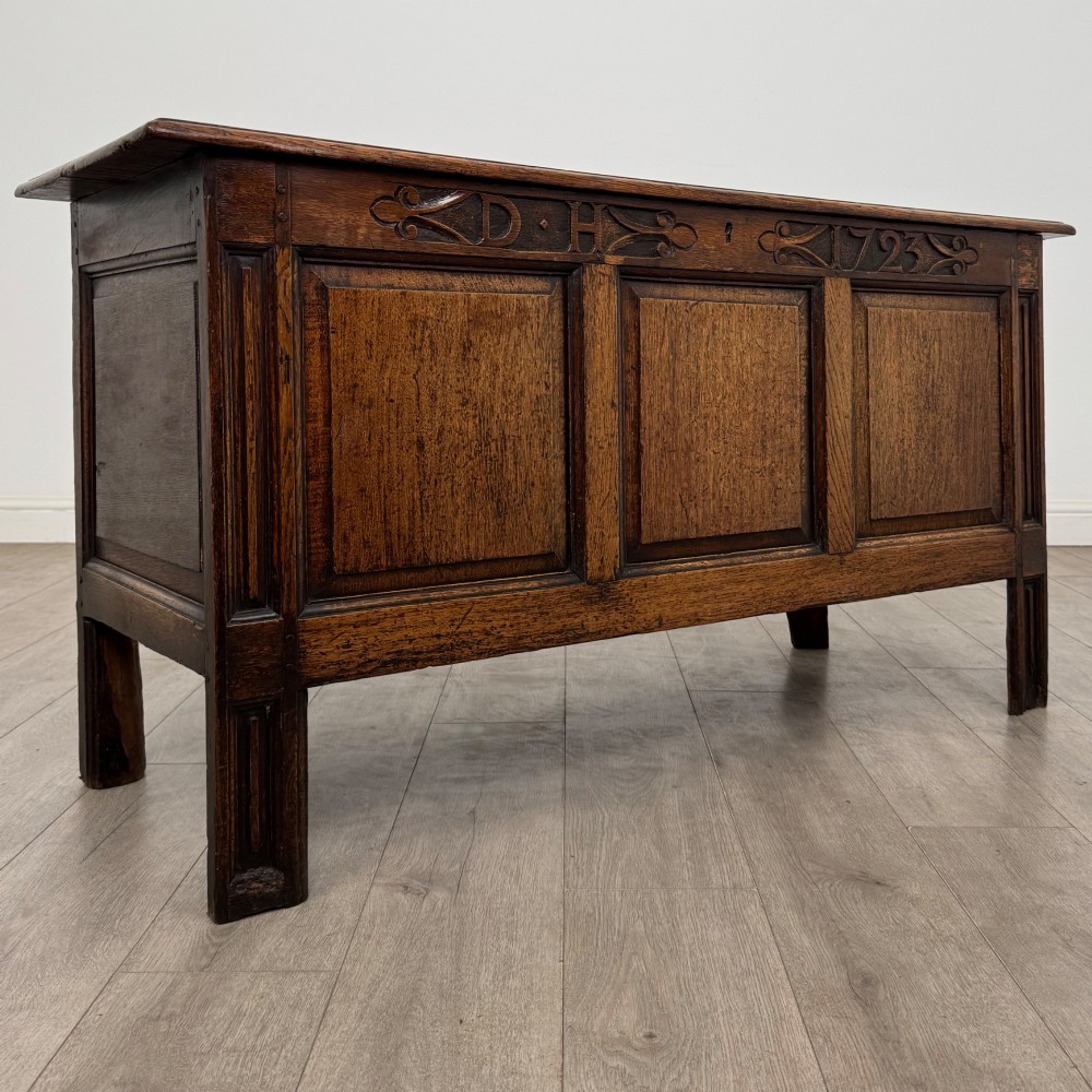 An 18th-century Georgian golden oak coffer featuring three raised panel front section and a carved top rail dated 1723 with initials D H. View VIII