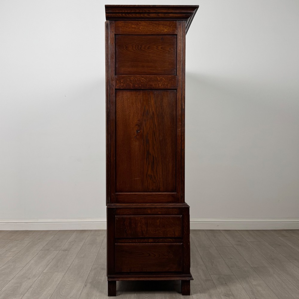 A dark oak double wardrobe featuring panelled doors set above four drawers with decorative brass drop handles. View VIII