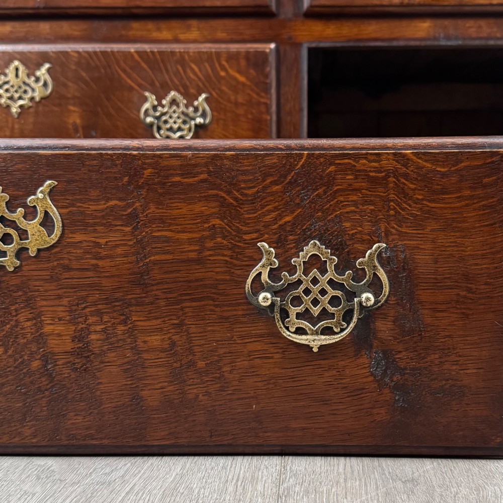 A dark oak double wardrobe featuring panelled doors set above four drawers with decorative brass drop handles. View XI