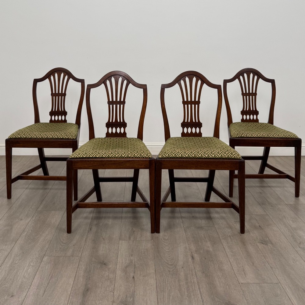 A set of four 18th-century Georgian mahogany dining chairs featuring pierced vertical back splats and green patterned drop-in seats.