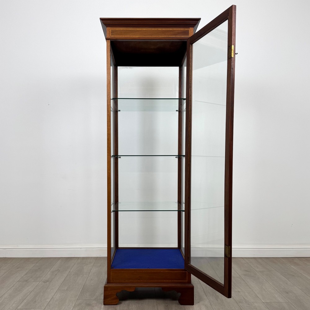 A tall early twentieth-century mahogany display cabinet featuring glazed sides, glass shelves, geometric string inlay, and bracket feet. View II