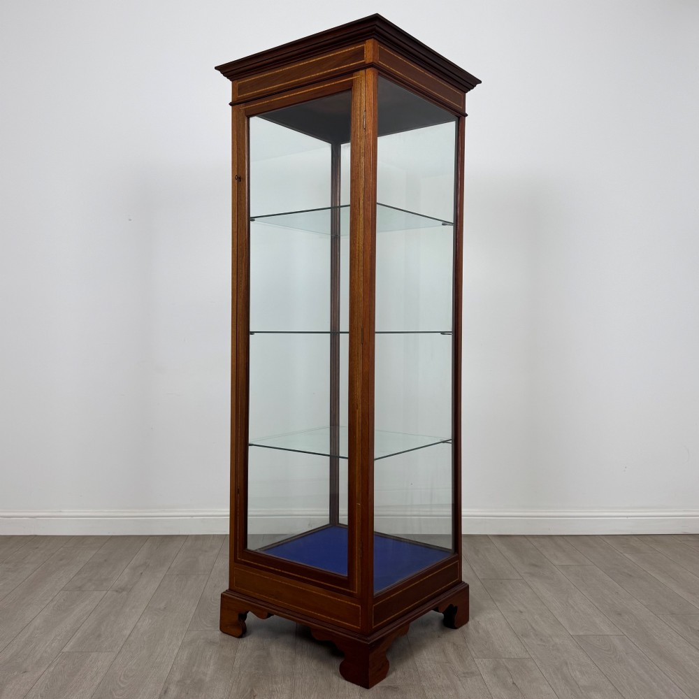 A tall early twentieth-century mahogany display cabinet featuring glazed sides, glass shelves, geometric string inlay, and bracket feet. View III