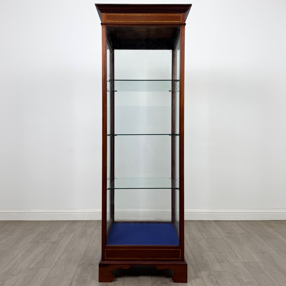A tall early twentieth-century mahogany display cabinet featuring glazed sides, glass shelves, geometric string inlay, and bracket feet. View IV