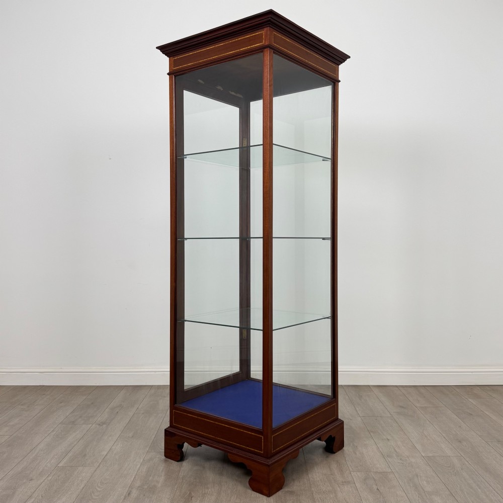 A tall early twentieth-century mahogany display cabinet featuring glazed sides, glass shelves, geometric string inlay, and bracket feet. View V
