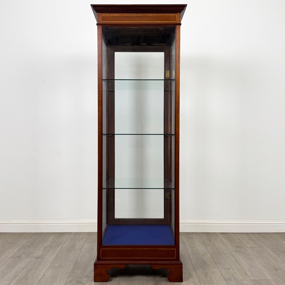 A tall early twentieth-century mahogany display cabinet featuring glazed sides, glass shelves, geometric string inlay, and bracket feet. View VI