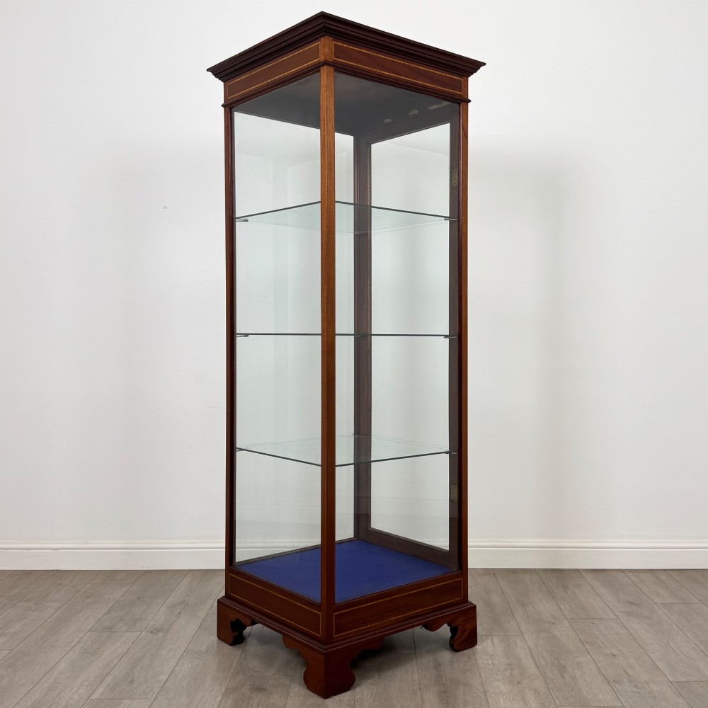 A tall early twentieth-century mahogany display cabinet featuring glazed sides, glass shelves, geometric string inlay, and bracket feet. View VII