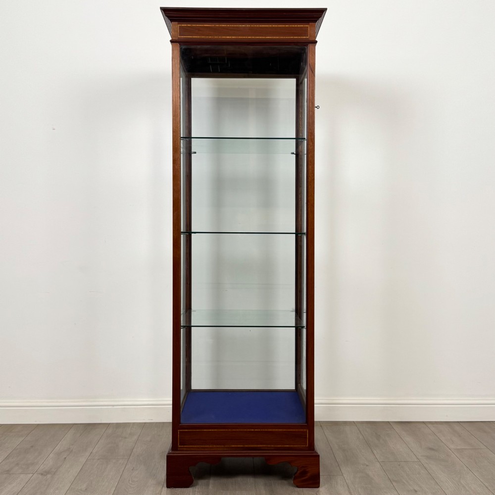 A tall early twentieth-century mahogany display cabinet featuring glazed sides, glass shelves, geometric string inlay, and bracket feet. View VIII