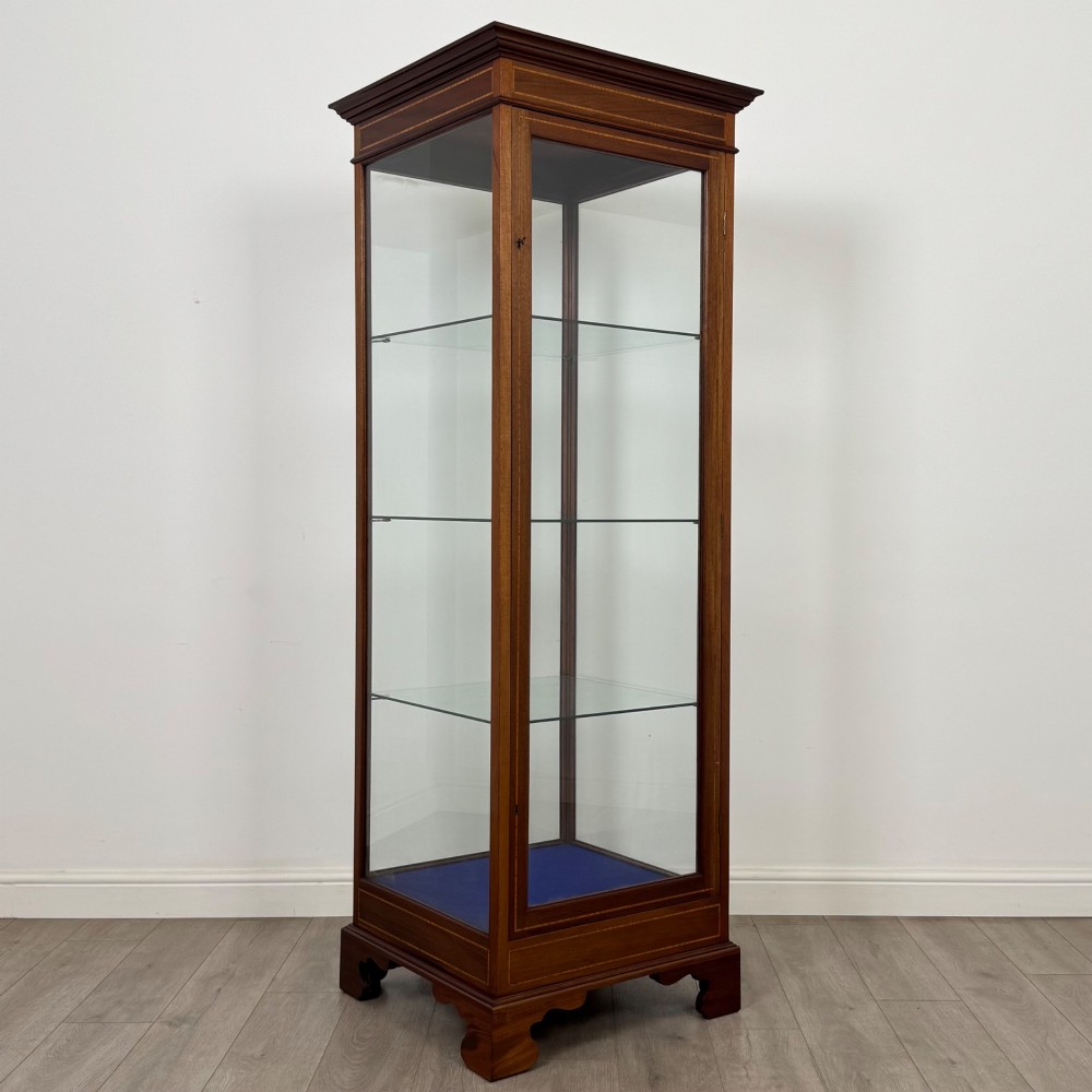 A tall early twentieth-century mahogany display cabinet featuring glazed sides, glass shelves, geometric string inlay, and bracket feet. View IX