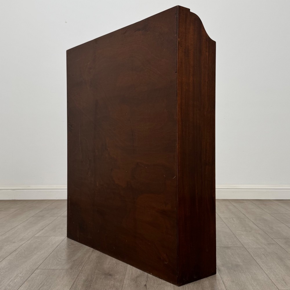 A dark mahogany open bookcase featuring three broad fixed shelves, shaped gallery side panels, and a subtle wave-formed lower apron. View VII