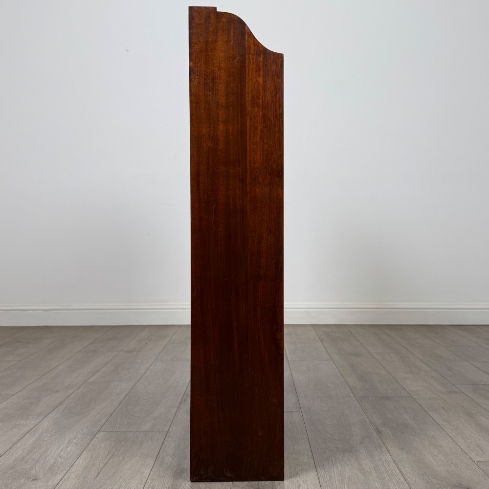 A dark mahogany open bookcase featuring three broad fixed shelves, shaped gallery side panels, and a subtle wave-formed lower apron. View VIII