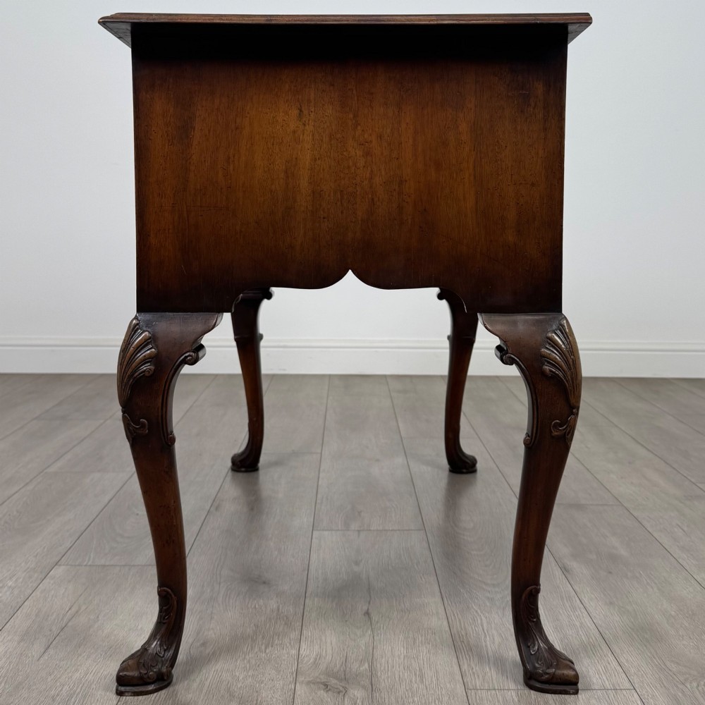 A Queen Anne style burr walnut writing table featuring cabriole legs, three front drawers with brass drop handles, and an arched kneehole. View III