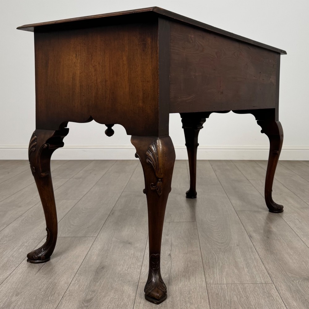 A Queen Anne style burr walnut writing table featuring cabriole legs, three front drawers with brass drop handles, and an arched kneehole. View IV