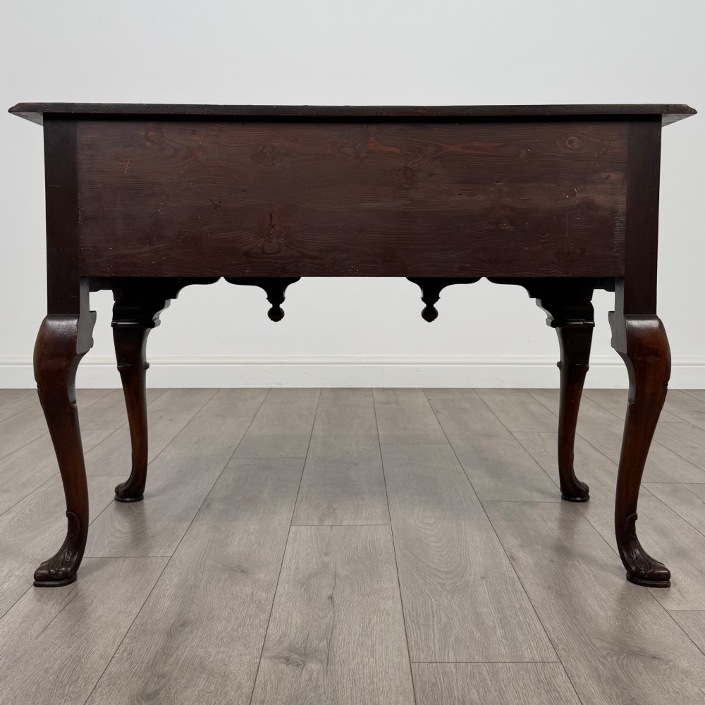 A Queen Anne style burr walnut writing table featuring cabriole legs, three front drawers with brass drop handles, and an arched kneehole. View V