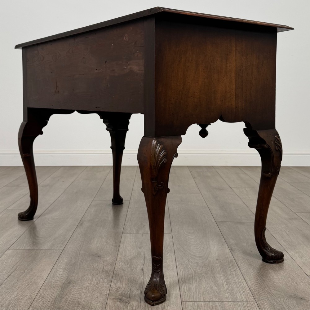 A Queen Anne style burr walnut writing table featuring cabriole legs, three front drawers with brass drop handles, and an arched kneehole. View VI