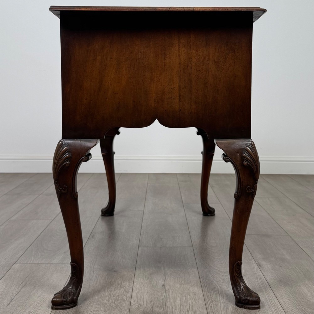 A Queen Anne style burr walnut writing table featuring cabriole legs, three front drawers with brass drop handles, and an arched kneehole. View VII