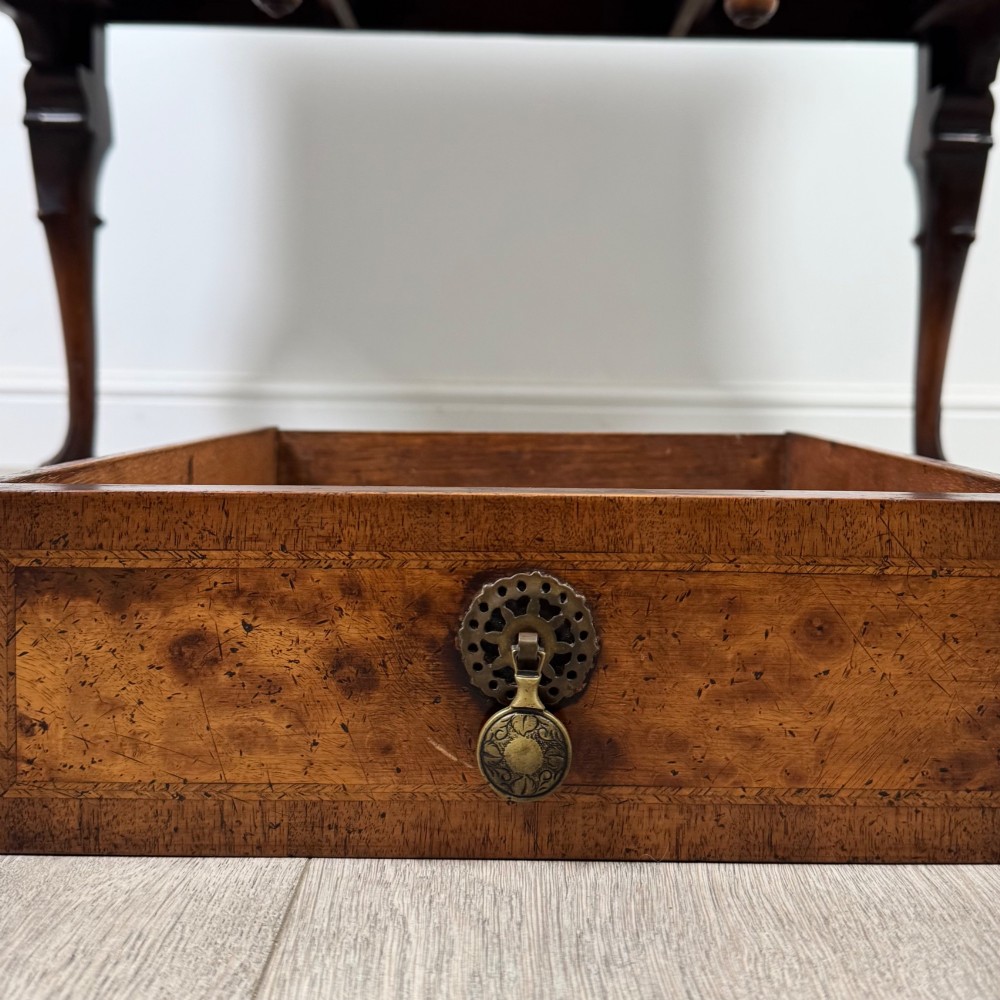A Queen Anne style burr walnut writing table featuring cabriole legs, three front drawers with brass drop handles, and an arched kneehole. View XI