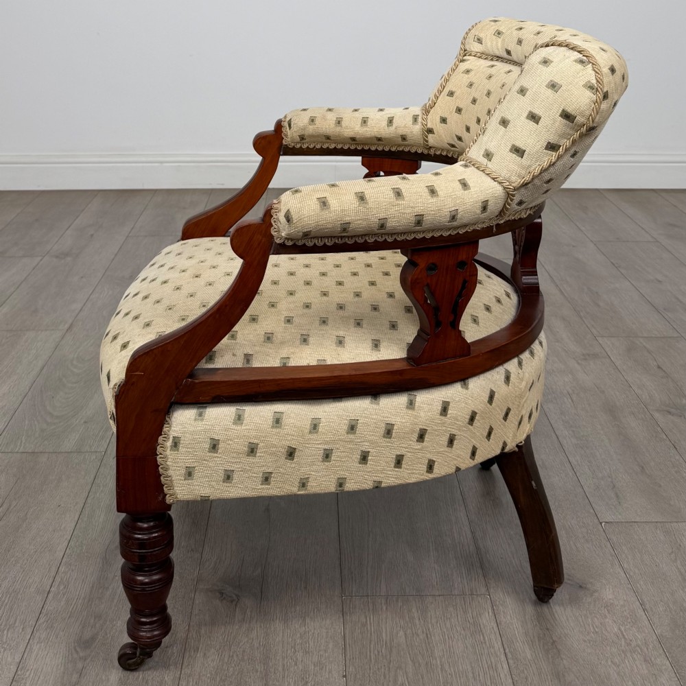 A pair of Edwardian mahogany tub chairs upholstered in a patterned cream fabric with turned front legs on castors. View III