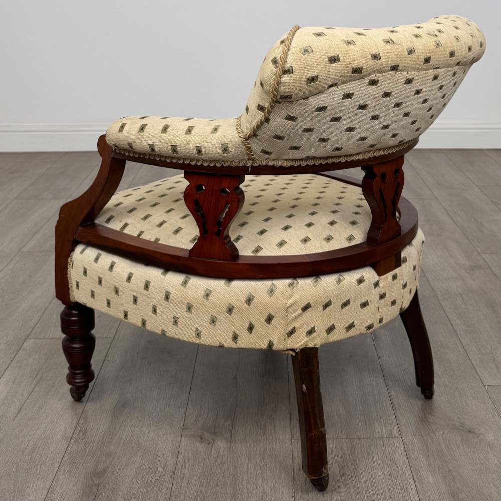 A pair of Edwardian mahogany tub chairs upholstered in a patterned cream fabric with turned front legs on castors. View IV