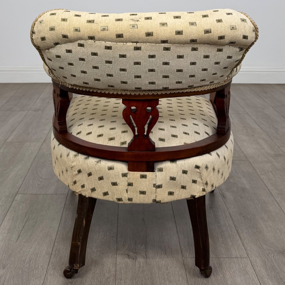 A pair of Edwardian mahogany tub chairs upholstered in a patterned cream fabric with turned front legs on castors. View V