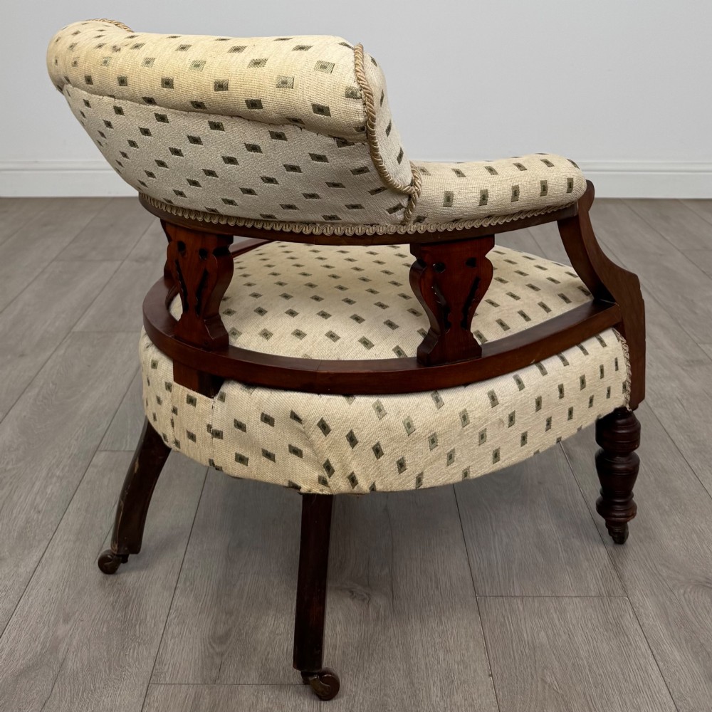 A pair of Edwardian mahogany tub chairs upholstered in a patterned cream fabric with turned front legs on castors. View VI