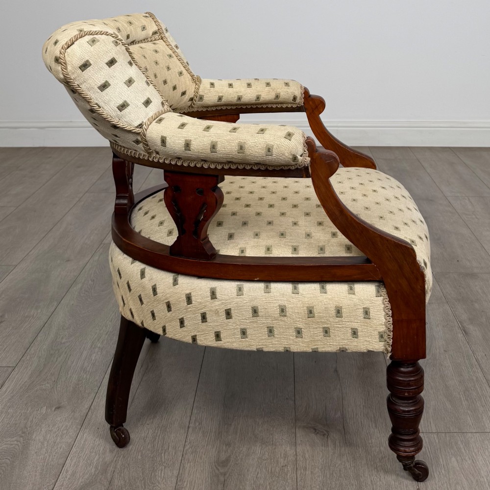 A pair of Edwardian mahogany tub chairs upholstered in a patterned cream fabric with turned front legs on castors. View VII