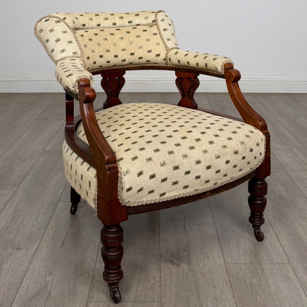 A pair of Edwardian mahogany tub chairs upholstered in a patterned cream fabric with turned front legs on castors. View VIII