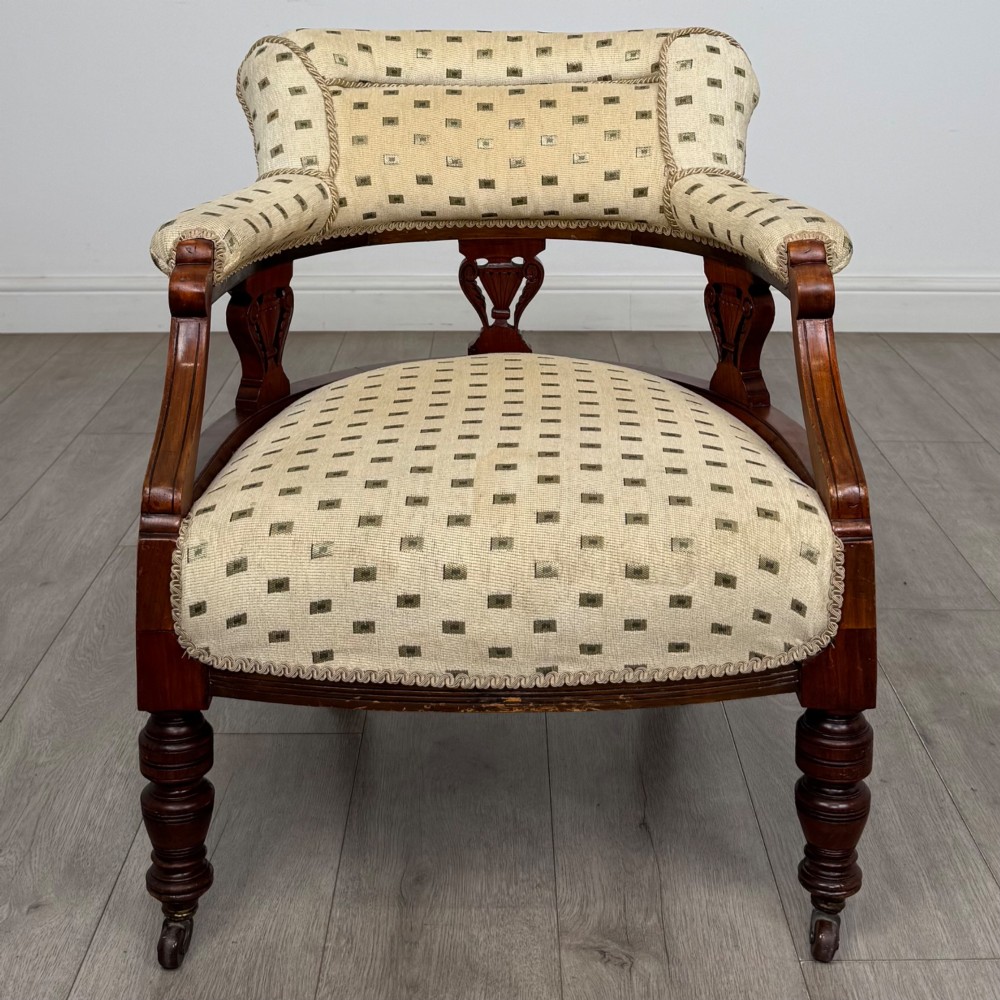 A pair of Edwardian mahogany tub chairs upholstered in a patterned cream fabric with turned front legs on castors. View IX