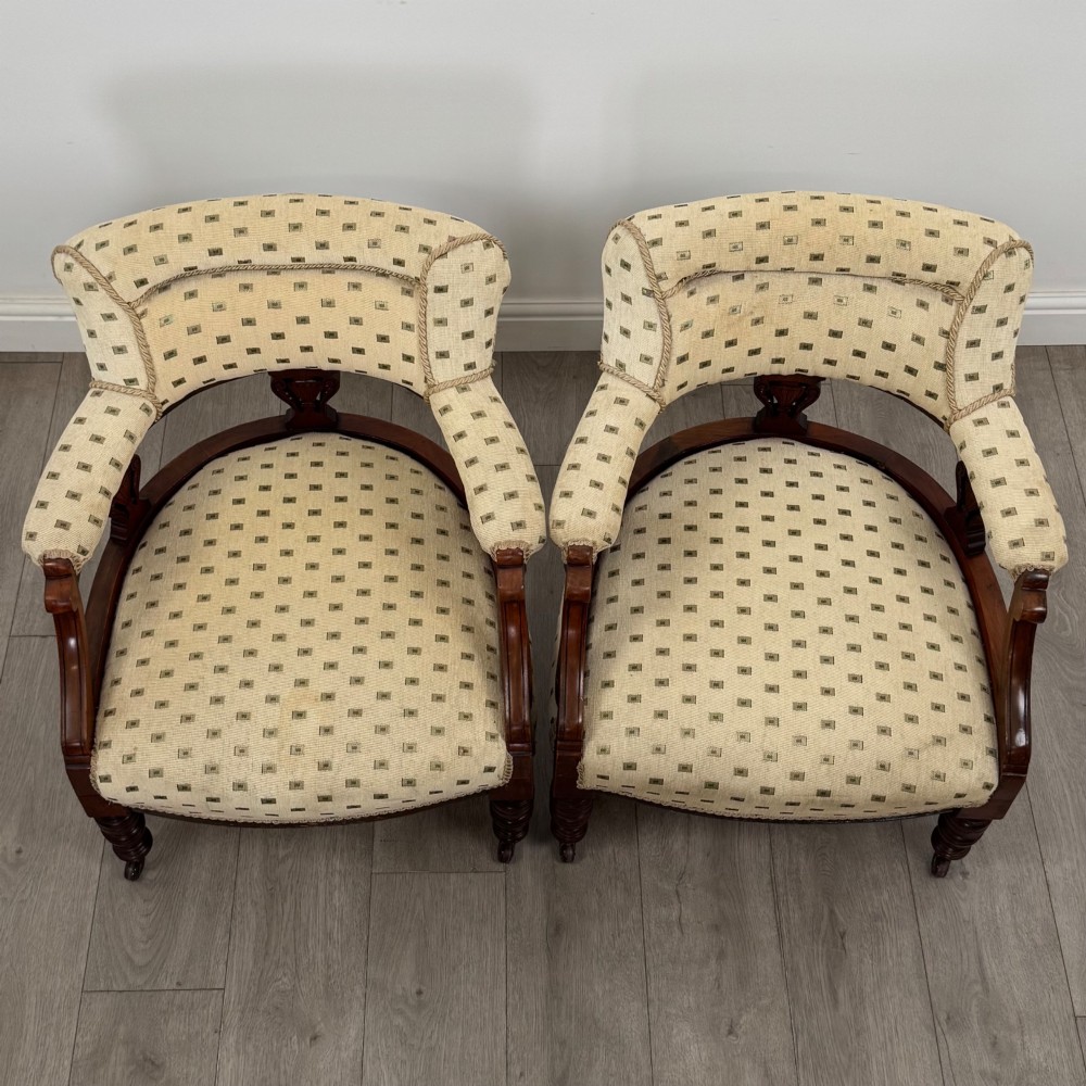 A pair of Edwardian mahogany tub chairs upholstered in a patterned cream fabric with turned front legs on castors. View X