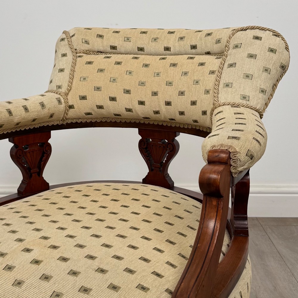 A pair of Edwardian mahogany tub chairs upholstered in a patterned cream fabric with turned front legs on castors. View XI
