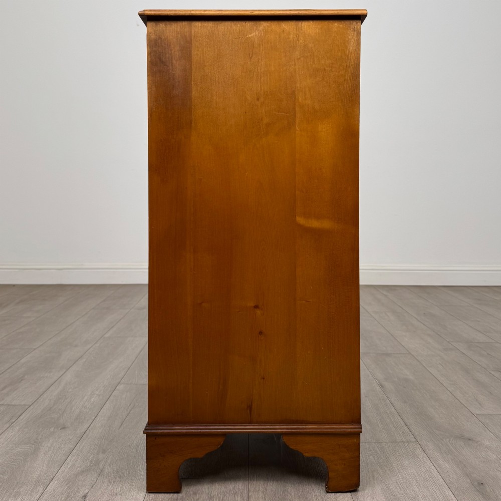 A tall 20th-century yew wood chest of drawers featuring two short drawers over four long graduated drawers with brass drop handles and bracket feet. View III