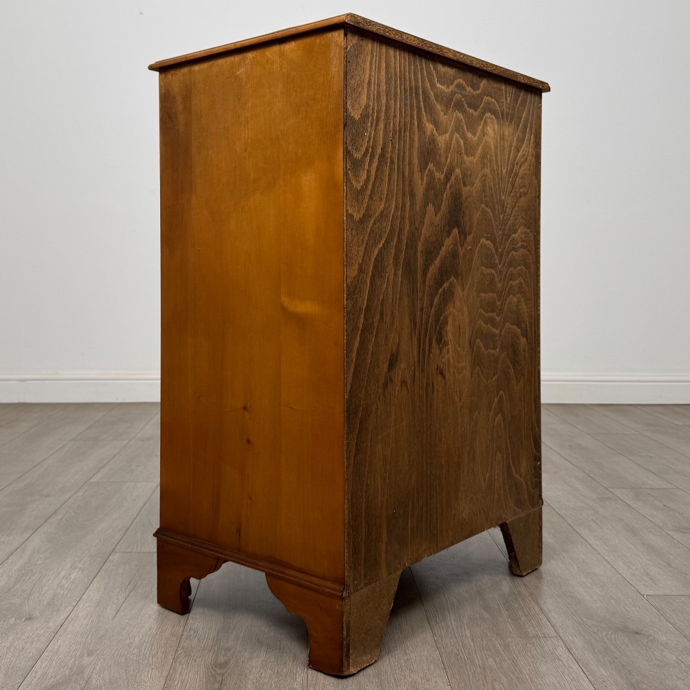 A tall 20th-century yew wood chest of drawers featuring two short drawers over four long graduated drawers with brass drop handles and bracket feet. View IV
