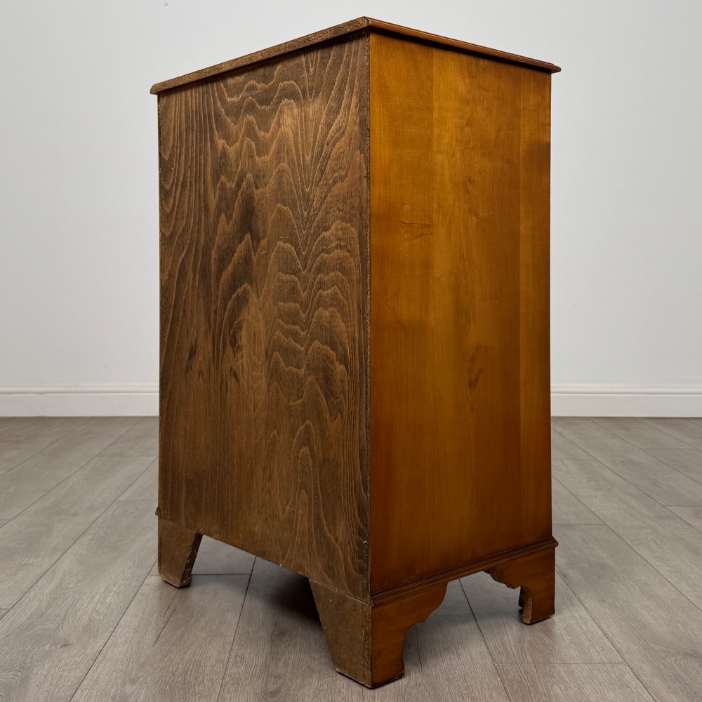 A tall 20th-century yew wood chest of drawers featuring two short drawers over four long graduated drawers with brass drop handles and bracket feet. View VI
