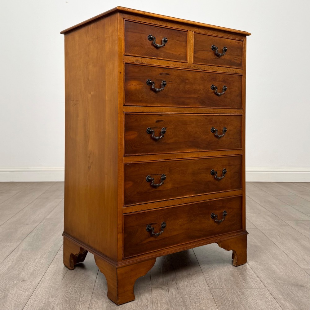A tall 20th-century yew wood chest of drawers featuring two short drawers over four long graduated drawers with brass drop handles and bracket feet. View VIII