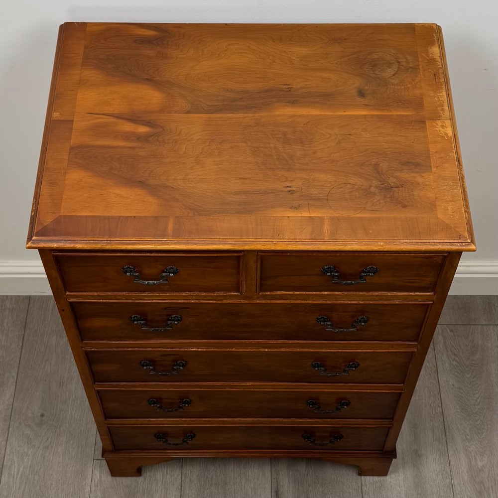 A tall 20th-century yew wood chest of drawers featuring two short drawers over four long graduated drawers with brass drop handles and bracket feet. View IX