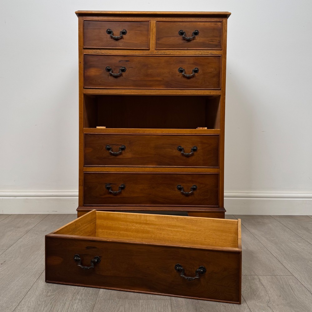 A tall 20th-century yew wood chest of drawers featuring two short drawers over four long graduated drawers with brass drop handles and bracket feet. View X