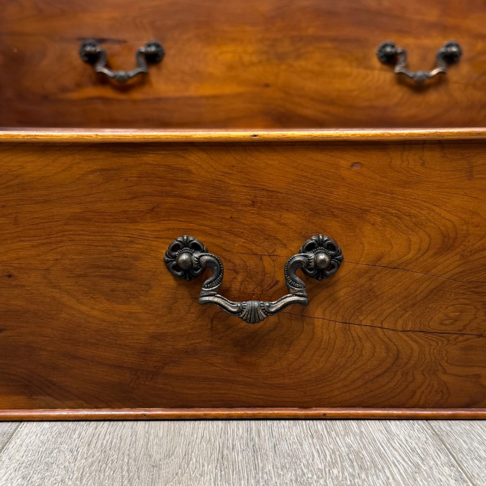 A tall 20th-century yew wood chest of drawers featuring two short drawers over four long graduated drawers with brass drop handles and bracket feet. View XI