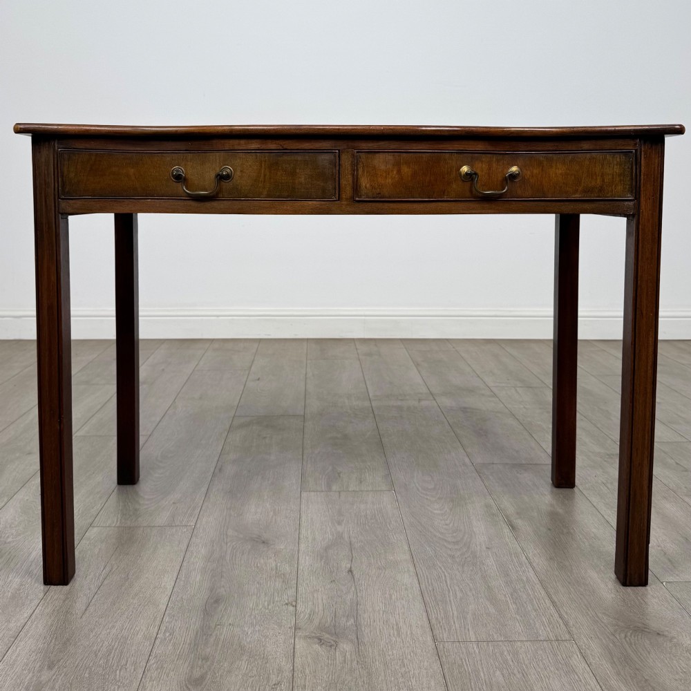 A 19th-century mahogany writing table with a curved serpentine front edge, two drawers with brass handles, and square legs.