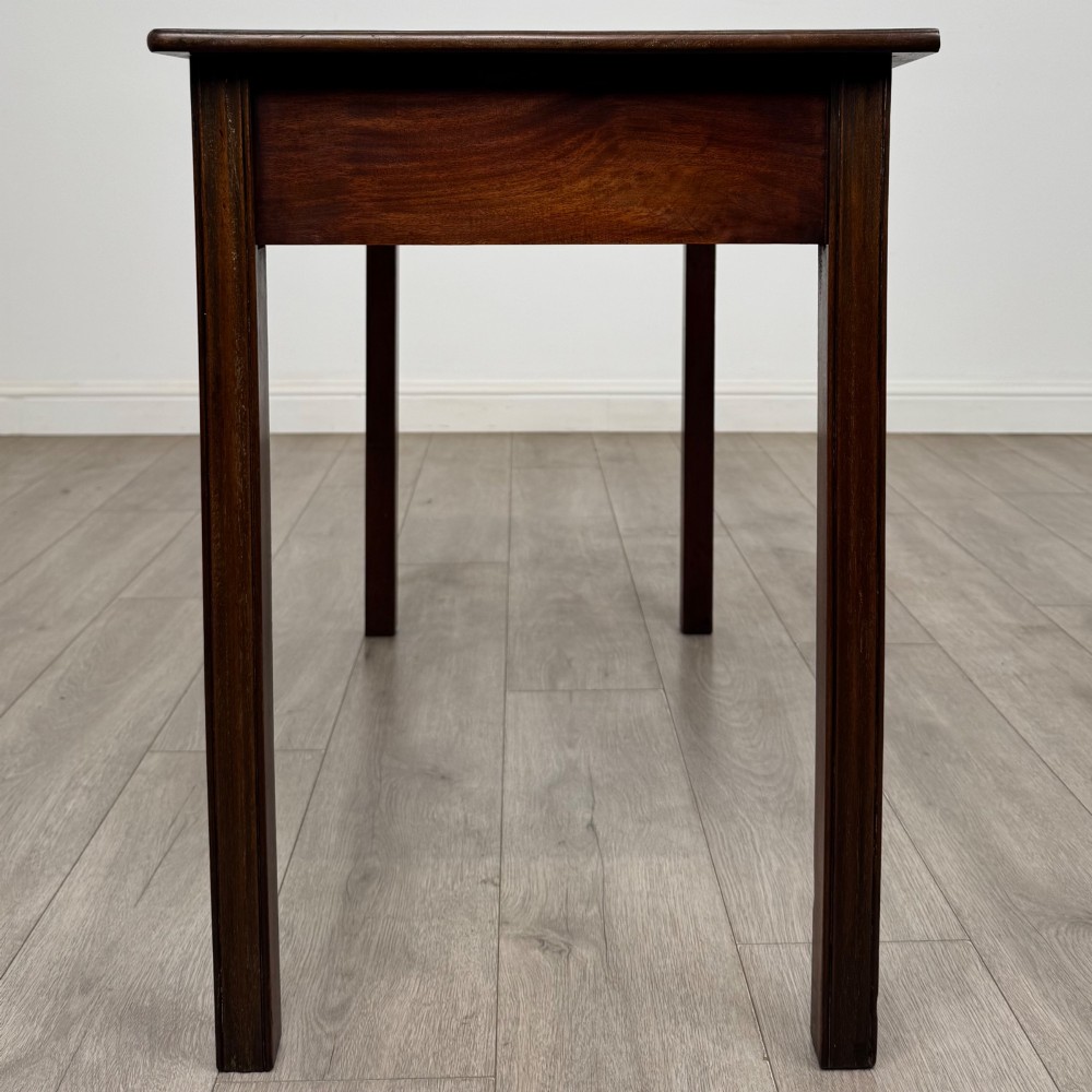 A 19th-century mahogany writing table with a curved serpentine front edge, two drawers with brass handles, and square legs. View III