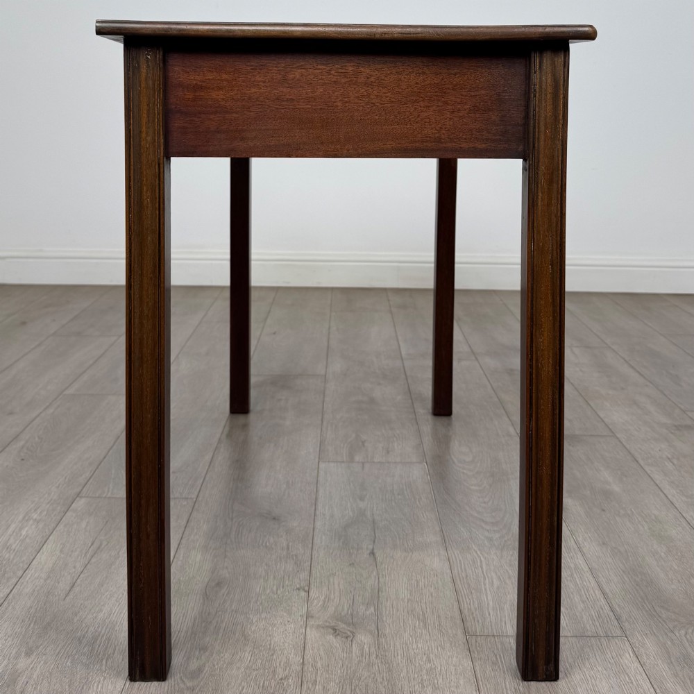 A 19th-century mahogany writing table with a curved serpentine front edge, two drawers with brass handles, and square legs. View VII