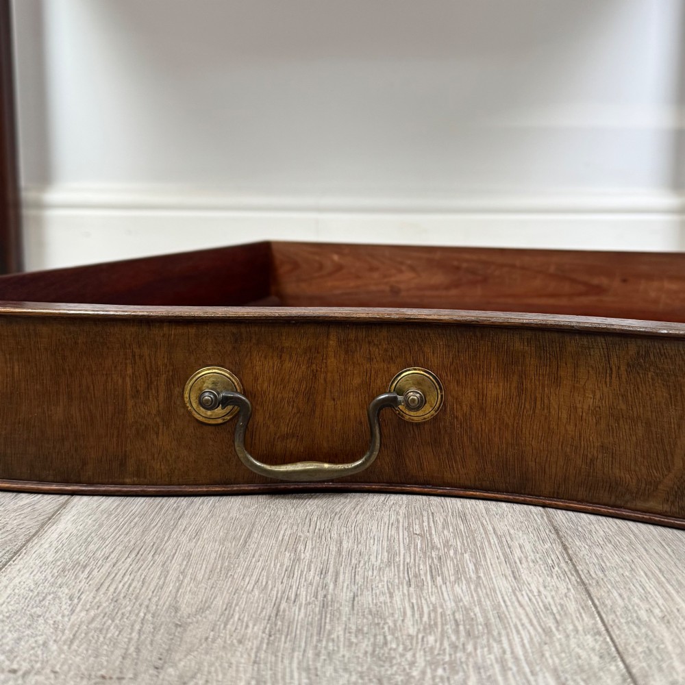A 19th-century mahogany writing table with a curved serpentine front edge, two drawers with brass handles, and square legs. View XI